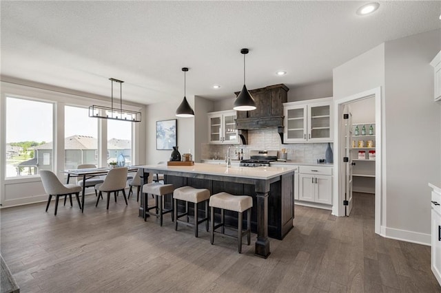 19477 W 114th Ter, Olathe, KS 66061 - kitchen with stainless steel range oven, dark wood-type flooring, light countertops, an island with sink, and tasteful backsplash