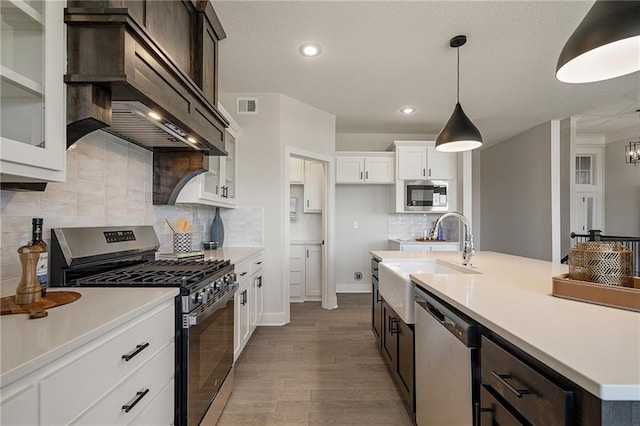 19477 W 114th Ter, Olathe, KS 66061 - kitchen featuring appliances with stainless steel finishes, premium range hood, dark wood-style flooring, light countertops, and recessed lighting