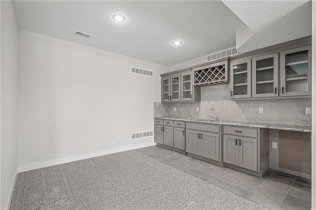 19477 W 114th Ter, Olathe, KS 66061 - kitchen with gray cabinets, recessed lighting, backsplash, glass insert cabinets, and light stone countertops