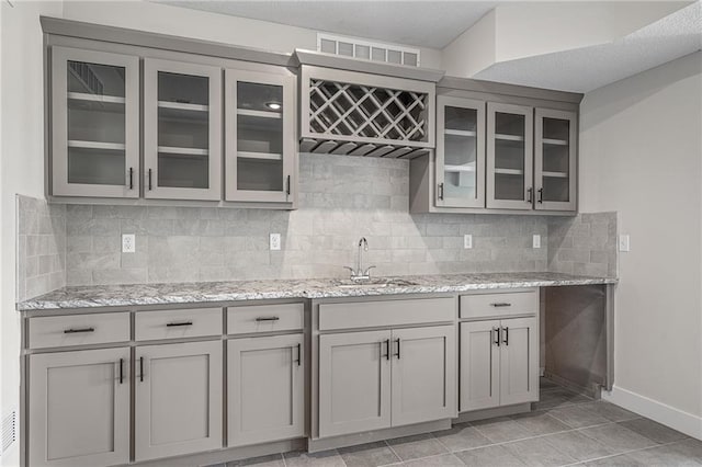19477 W 114th Ter, Olathe, KS 66061 - kitchen with gray cabinetry, glass insert cabinets, and light stone counters