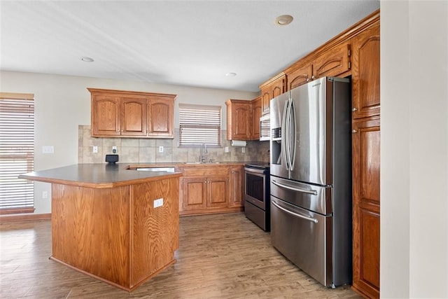 601 W 3rd Ter, Wellsville, KS 66092 - kitchen featuring stainless steel appliances, a sink, backsplash, light wood finished floors, and brown cabinetry