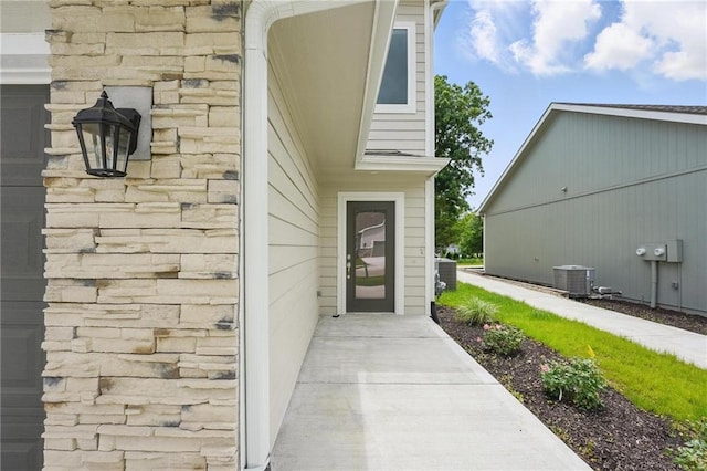 801 Highland Dr, Edwardsville, KS 66111 - doorway to property with central AC unit and stone siding