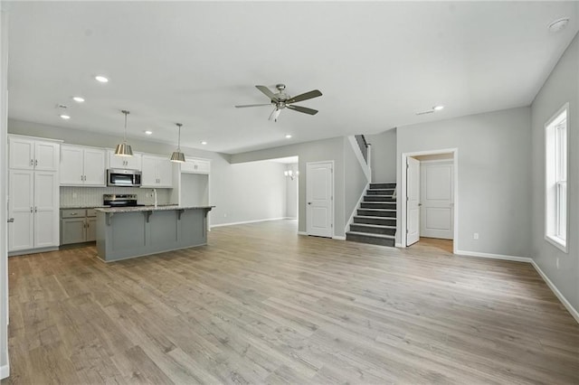 801 Highland Dr, Edwardsville, KS 66111 - unfurnished living room with recessed lighting, ceiling fan, stairs, baseboards, and light wood-type flooring