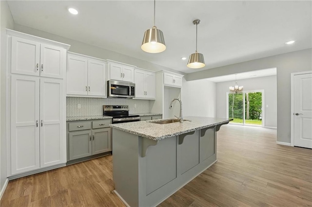 801 Highland Dr, Edwardsville, KS 66111 - kitchen with appliances with stainless steel finishes, a sink, light wood-style floors, decorative backsplash, and recessed lighting