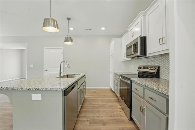 801 Highland Dr, Edwardsville, KS 66111 - kitchen featuring appliances with stainless steel finishes, a sink, a kitchen island with sink, light wood-type flooring, and white cabinets