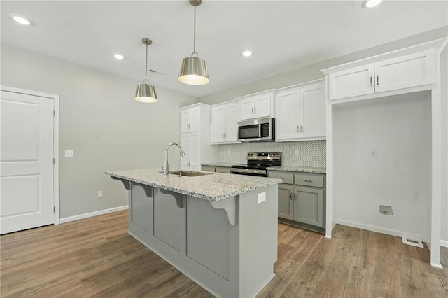 801 Highland Dr, Edwardsville, KS 66111 - kitchen featuring appliances with stainless steel finishes, a sink, a center island with sink, tasteful backsplash, and a breakfast bar area