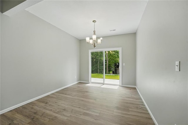 801 Highland Dr, Edwardsville, KS 66111 - empty room featuring a chandelier, wood finished floors, and baseboards