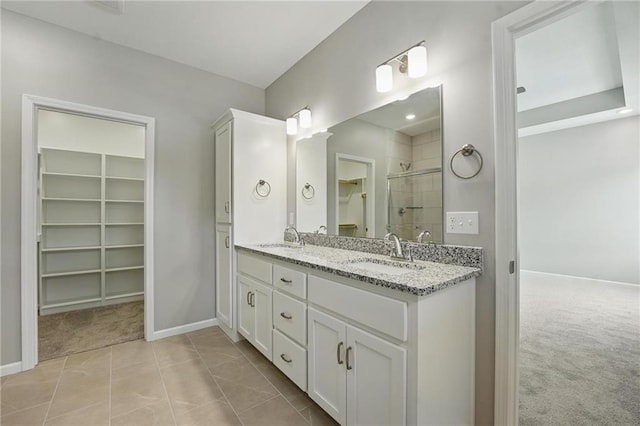 801 Highland Dr, Edwardsville, KS 66111 - full bathroom featuring a spacious closet, double vanity, tiled shower, baseboards, and tile patterned floors