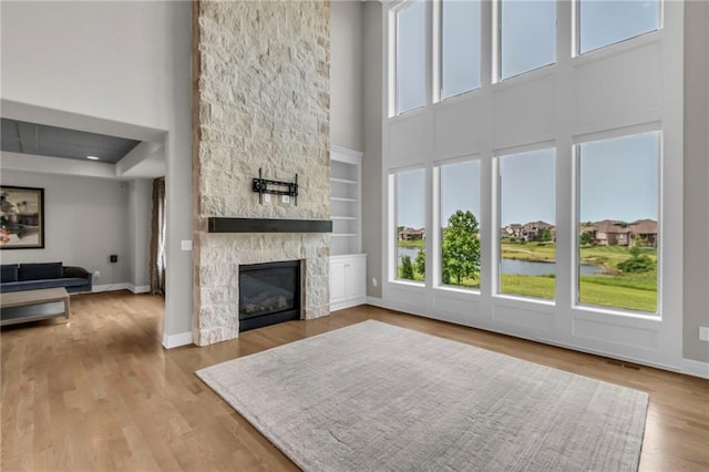 9812 Saddletop St, Lenexa, KS 66227 - unfurnished living room featuring a towering ceiling, plenty of natural light, a stone fireplace, and wood finished floors