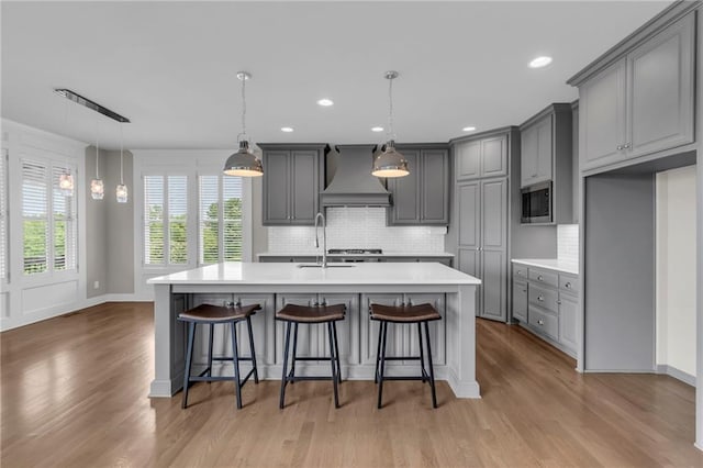 9812 Saddletop St, Lenexa, KS 66227 - kitchen featuring custom exhaust hood, gray cabinets, light countertops, decorative backsplash, and light wood-style flooring