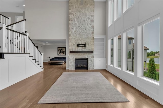 9812 Saddletop St, Lenexa, KS 66227 - unfurnished living room featuring a high ceiling, stairway, wood finished floors, a stone fireplace, and recessed lighting