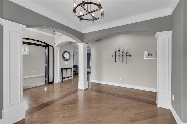9812 Saddletop St, Lenexa, KS 66227 - spare room featuring decorative columns, a chandelier, wood finished floors, ornamental molding, and arched walkways