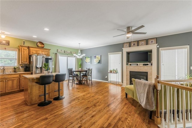 2420 SW Golden Eagle Rd, Lees Summit, MO 64082 - kitchen featuring stainless steel refrigerator with ice dispenser, brown cabinetry, a kitchen island, a kitchen bar, and crown molding