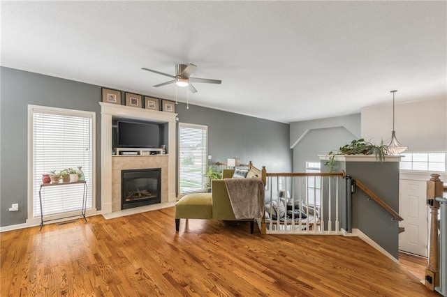 2420 SW Golden Eagle Rd, Lees Summit, MO 64082 - living area with a ceiling fan, wood finished floors, a tiled fireplace, and baseboards