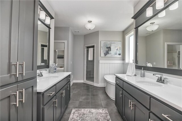 5858 Mccormick Dr, Shawnee, KS 66226 - full bathroom featuring two vanities, a stall shower, a freestanding tub, tile patterned floors, and baseboards