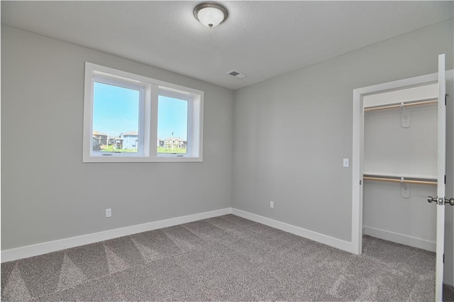 5858 Mccormick Dr, Shawnee, KS 66226 - unfurnished bedroom with carpet floors, a closet, baseboards, a textured ceiling, and a walk in closet