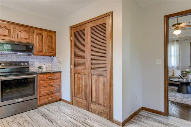 15215 Edgerton Rd, Gardner, KS 66030 - kitchen featuring appliances with stainless steel finishes, decorative backsplash, brown cabinetry, and baseboards