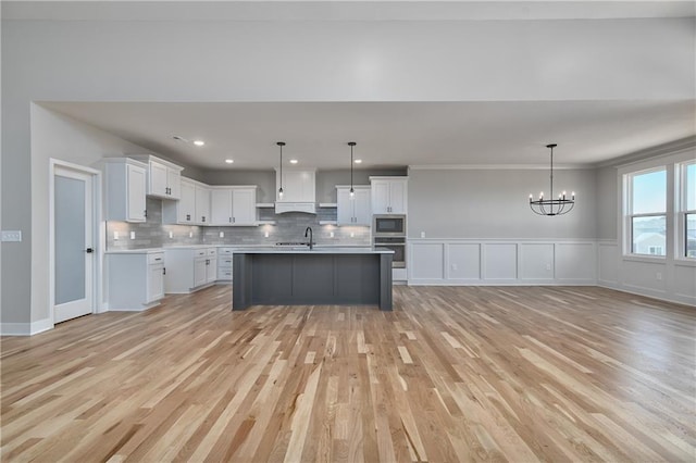 6031 Apache St, Shawnee, KS 66226 - kitchen with stainless steel appliances, a sink, light wood-style flooring, a chandelier, and decorative backsplash
