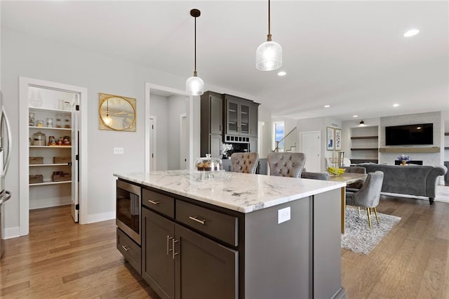 4820 NE 90th Ter, Kansas City, MO 64156 - kitchen featuring stainless steel microwave, light wood-style floors, pendant lighting, a center island, and recessed lighting