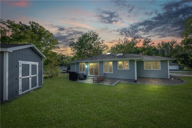 513 Brown Circle Dr, Osawatomie, KS 66064 - back of property at dusk with a lawn, a storage shed, and a patio area