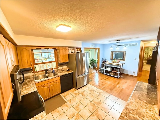 513 Brown Circle Dr, Osawatomie, KS 66064 - kitchen featuring freestanding refrigerator, dishwasher, light tile patterned floors, a textured ceiling, and brown cabinets