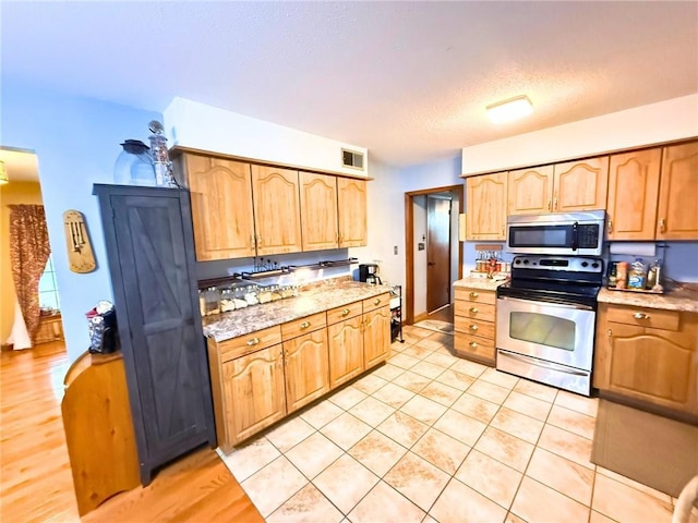 513 Brown Circle Dr, Osawatomie, KS 66064 - kitchen featuring stainless steel appliances, a textured ceiling, light tile patterned flooring, and light stone counters