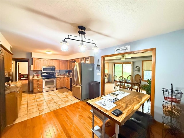 513 Brown Circle Dr, Osawatomie, KS 66064 - kitchen featuring stainless steel appliances, a ceiling fan, light wood-style floors, light countertops, and a textured ceiling
