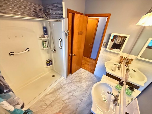 513 Brown Circle Dr, Osawatomie, KS 66064 - bathroom featuring marble look tile flooring, a shower stall, double vanity, and tile walls