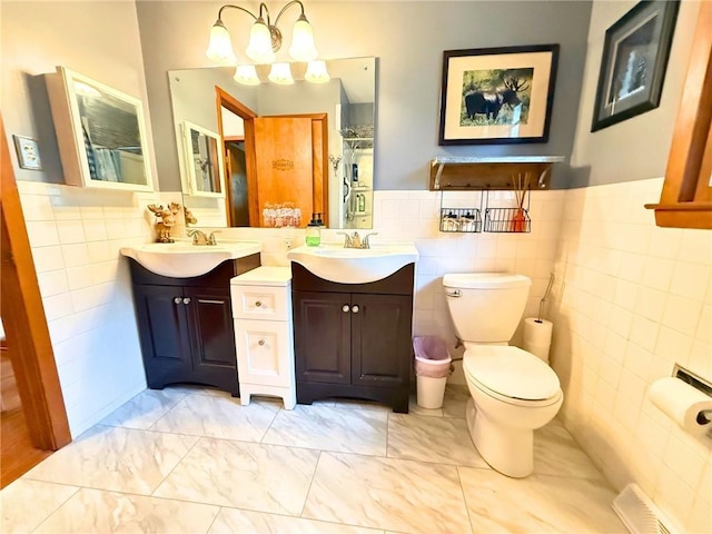 513 Brown Circle Dr, Osawatomie, KS 66064 - bathroom with tile walls, two vanities, marble look tile flooring, wainscoting, and a chandelier