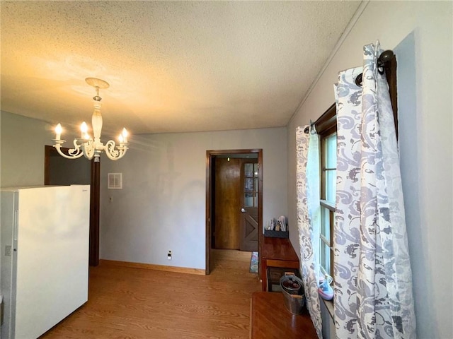513 Brown Circle Dr, Osawatomie, KS 66064 - unfurnished dining area featuring wood finished floors, a chandelier, and a textured ceiling