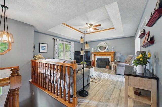 1453 Madison St, Lees Summit, MO 64081 - living area featuring a tray ceiling, a ceiling fan, wood finished floors, a tile fireplace, and a textured ceiling