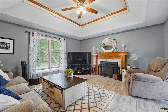 1453 Madison St, Lees Summit, MO 64081 - living room with a raised ceiling, light wood-type flooring, ceiling fan, a fireplace, and crown molding