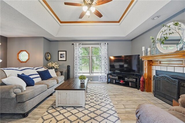 1453 Madison St, Lees Summit, MO 64081 - living area with wood finished floors, a tile fireplace, a raised ceiling, a ceiling fan, and crown molding
