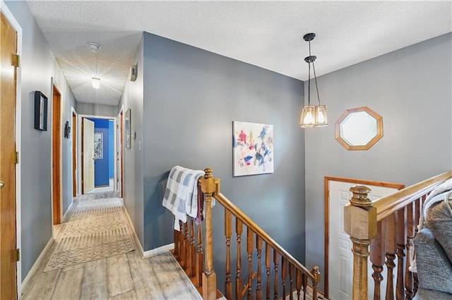 1453 Madison St, Lees Summit, MO 64081 - hall with an upstairs landing, wood finished floors, baseboards, and a textured ceiling
