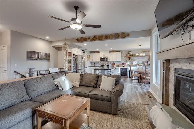 807 N Whispering Hills Dr, Lone Jack, MO 64070 - living area with a ceiling fan, light wood-type flooring, a chandelier, a stone fireplace, and recessed lighting