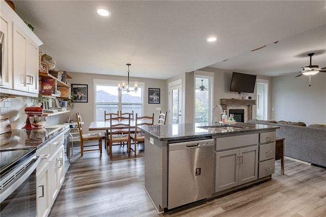 807 N Whispering Hills Dr, Lone Jack, MO 64070 - kitchen featuring appliances with stainless steel finishes, a fireplace, a sink, open floor plan, and light wood-type flooring