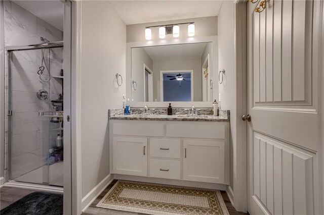 807 N Whispering Hills Dr, Lone Jack, MO 64070 - bathroom featuring double vanity, a shower stall, baseboards, and a ceiling fan