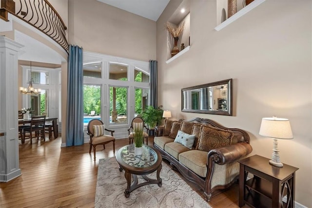11121 S Whitetail Ln, Olathe, KS 66061 - living room with a towering ceiling, a chandelier, wood-type flooring, and decorative columns