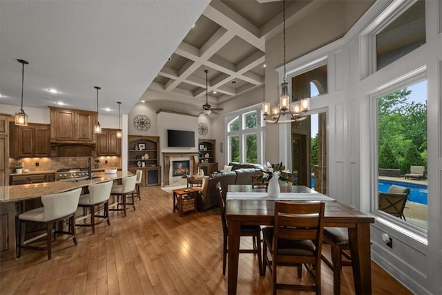 11121 S Whitetail Ln, Olathe, KS 66061 - dining area with ceiling fan, wood-type flooring, beamed ceiling, a glass covered fireplace, and coffered ceiling
