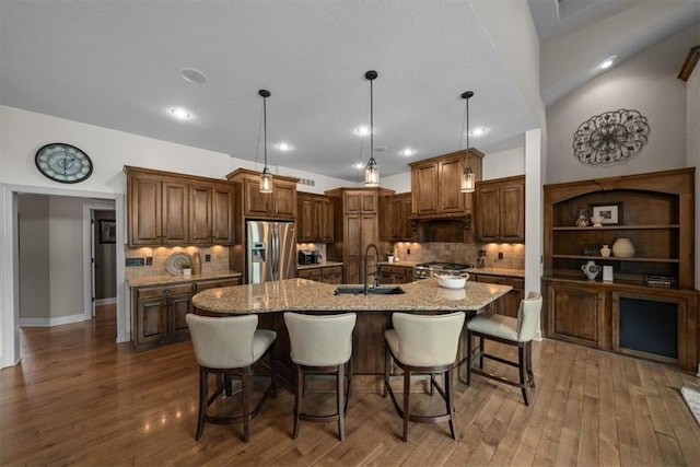 11121 S Whitetail Ln, Olathe, KS 66061 - kitchen with stainless steel refrigerator with ice dispenser, a breakfast bar area, tasteful backsplash, a spacious island, and wood finished floors