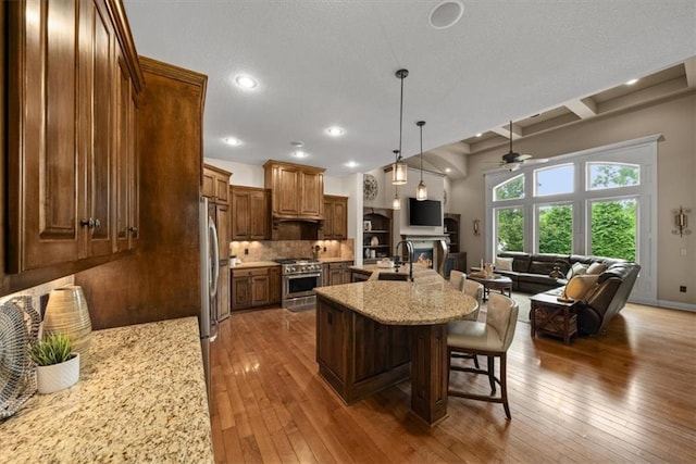 11121 S Whitetail Ln, Olathe, KS 66061 - kitchen with stainless steel appliances, open floor plan, a ceiling fan, a breakfast bar area, and hardwood / wood-style floors