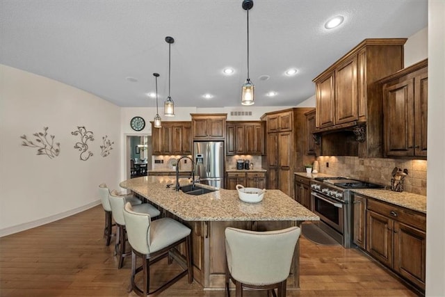11121 S Whitetail Ln, Olathe, KS 66061 - kitchen with stainless steel appliances, decorative backsplash, dark wood-style floors, a kitchen bar, and an island with sink