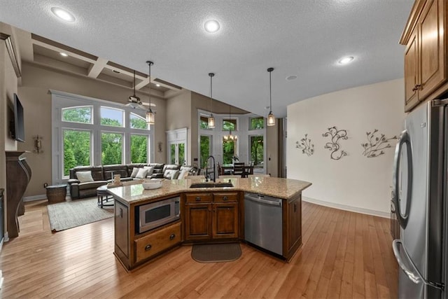 11121 S Whitetail Ln, Olathe, KS 66061 - kitchen with appliances with stainless steel finishes, light wood finished floors, coffered ceiling, brown cabinetry, and light stone countertops