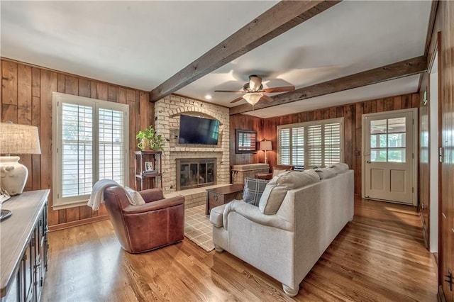 8911 W 105th Ter, Overland Park, KS 66212 - living area with wooden walls, wood finished floors, beam ceiling, a brick fireplace, and ceiling fan