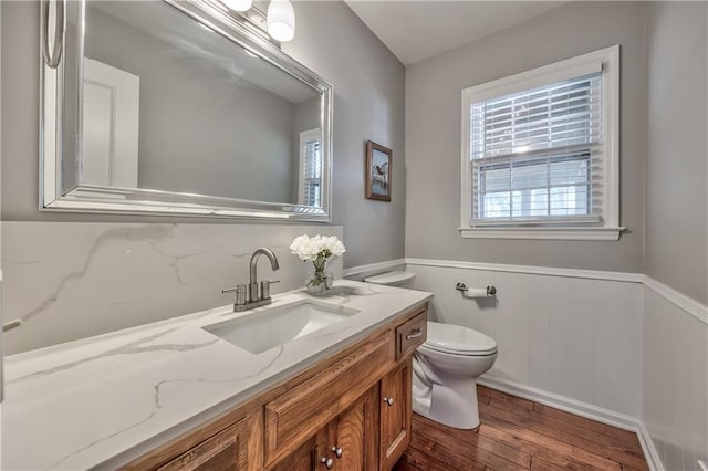 8911 W 105th Ter, Overland Park, KS 66212 - bathroom featuring a wainscoted wall, vanity, hardwood / wood-style flooring, and toilet