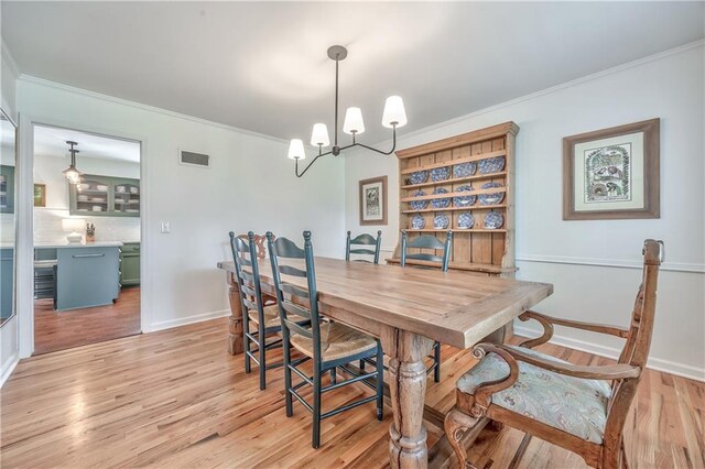 8911 W 105th Ter, Overland Park, KS 66212 - dining area with light wood-style flooring, crown molding, a chandelier, and baseboards