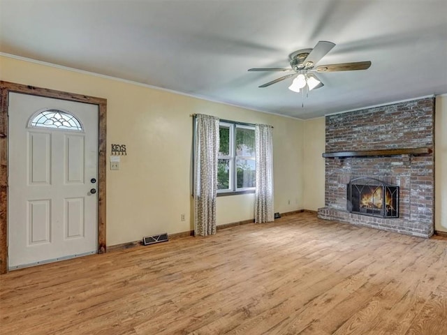 610 Morgan St, Lansing, KS 66043 - unfurnished living room featuring plenty of natural light, wood finished floors, ceiling fan, a brick fireplace, and crown molding