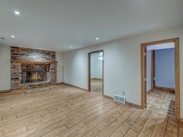 610 Morgan St, Lansing, KS 66043 - unfurnished living room with a brick fireplace, light wood-style floors, recessed lighting, and baseboards