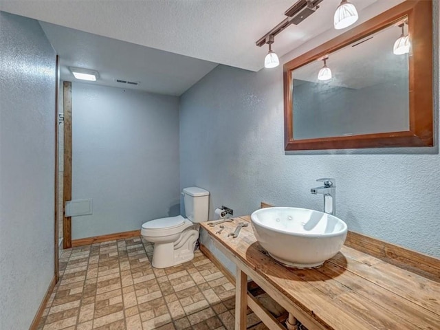 610 Morgan St, Lansing, KS 66043 - bathroom featuring a sink, a textured wall, baseboards, toilet, and a textured ceiling