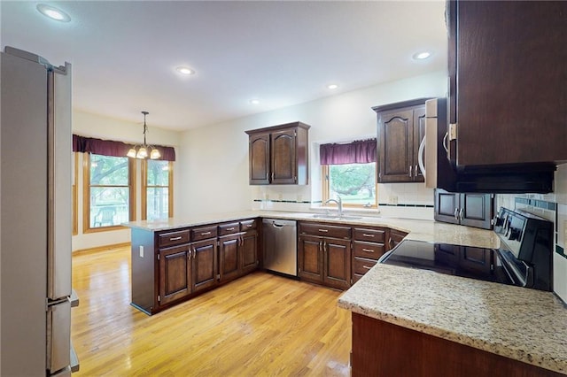 1404 NE Piedmont Dr, Lees Summit, MO 64064 - kitchen with appliances with stainless steel finishes, a peninsula, light wood-style flooring, a chandelier, and a sink